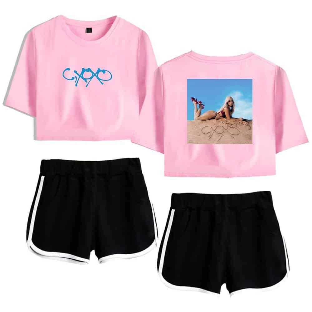 Bright pink cropped t-shirt with a blue graphic logo and a photo of a woman on the back, paired with black athletic shorts with white trim, inspired by Camila Cabello's casual style.